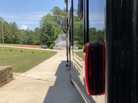 2015 Ford F-550 - The side of a large, dark vehicle is visible, parked on a driveway next to a grassy lawn.
