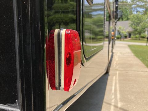 2015 Ford F-550 - Close-up of a red taillight assembly mounted on the side of a dark-colored vehicle.