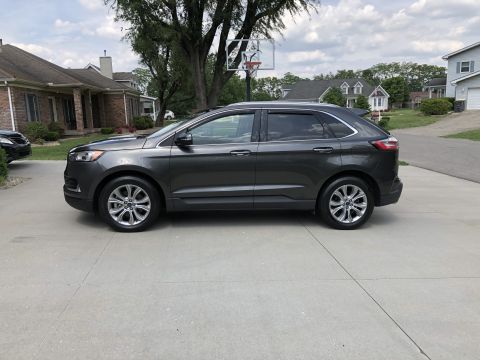 2019 Ford Everest - A dark gray Ford Edge is parked in a driveway with houses and trees in the background.