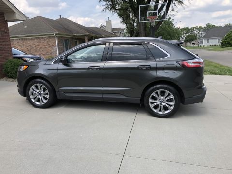 2019 Ford Everest - A dark gray Ford Edge SUV is parked on a concrete driveway in front of a house.