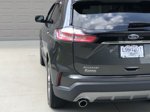 2019 Ford Everest - A dark gray Ford Edge SUV is viewed from the rear, parked in front of a garage door.