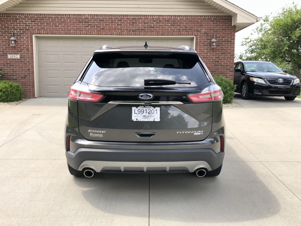Rear view of a 2019 Ford Edge Titanium SUV parked in a driveway. Another car is visible in the background