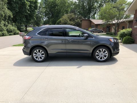 2019 Ford Everest - Side profile of a gray SUV parked on a concrete driveway with trees and houses in the background.