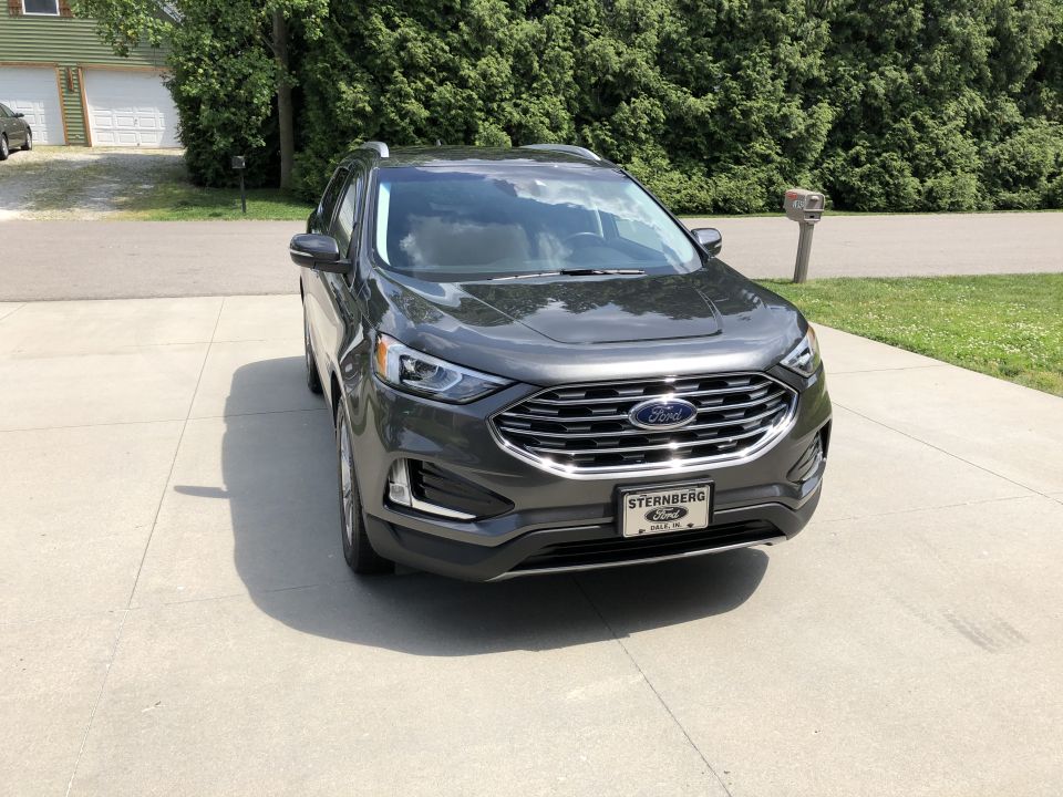 Dark gray Ford Edge SUV parked on a concrete driveway, front view