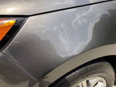2019 Ford Everest - A close-up shot of the metallic gray paint on the front fender and headlight assembly of a vehicle. Reflections of clouds and trees are vis…
