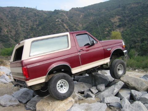 1985 Ford Bronco - This Ford Bronco is navigating a rocky trail, demonstrating its off-road capability.
