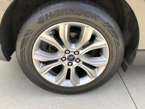 2019 Ford Everest - A close-up, low-angle shot shows the front passenger side wheel and tire of a vehicle. The tire is a Hankook brand, and the silver alloy wh…