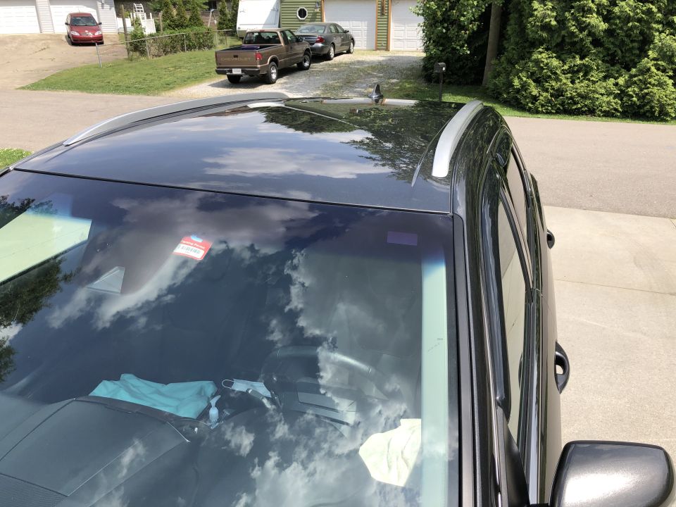 Dark gray SUV parked on a driveway, showing reflections on the windshield and roof.
