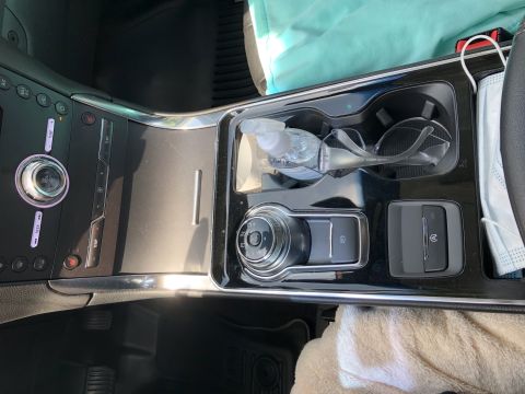 2019 Ford Everest - The interior of a car's center console shows a rotary gear selector, parking brake button, and a button for an electronic parking brake. A…