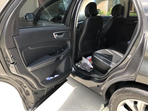 2019 Ford Everest - The interior of a dark-colored SUV is shown, with the front passenger door and rear passenger door open. The rear seats and part of the dri…