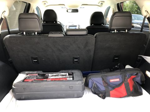 2019 Ford Everest - The interior of a Ford SUV's cargo area is shown, with the rear seats folded down. A black toolbox and a red and blue Craftsman tool bag ar…