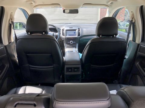 2019 Ford Everest - The interior of a modern SUV is shown from the back seat, looking forward towards the front seats and dashboard. The black leather seats an…