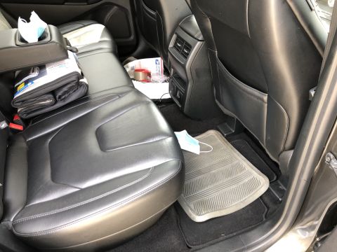 2019 Ford Everest - The interior of a Ford Everest is shown, focusing on the rear seats and floor. A folded blanket and a disposable face mask are visible on t…