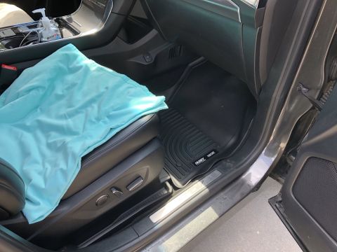 2019 Ford Everest - The interior of a car shows a light blue blanket draped over the passenger seat, with a black floor mat visible on the floor. A bottle of h…