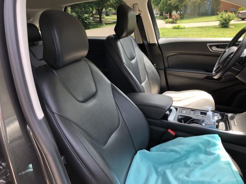 2019 Ford Everest - The interior of a modern SUV shows black leather seats, a center console with a hand sanitizer dispenser, and a light blue cloth draped ove…