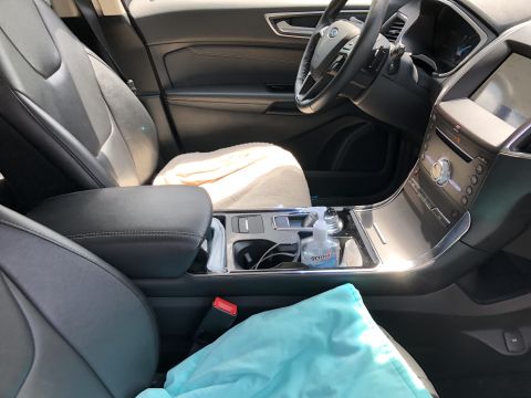 2019 Ford Everest - The interior of a modern SUV is shown, focusing on the center console and dashboard. Visible items include a hand sanitizer bottle, cup hol…
