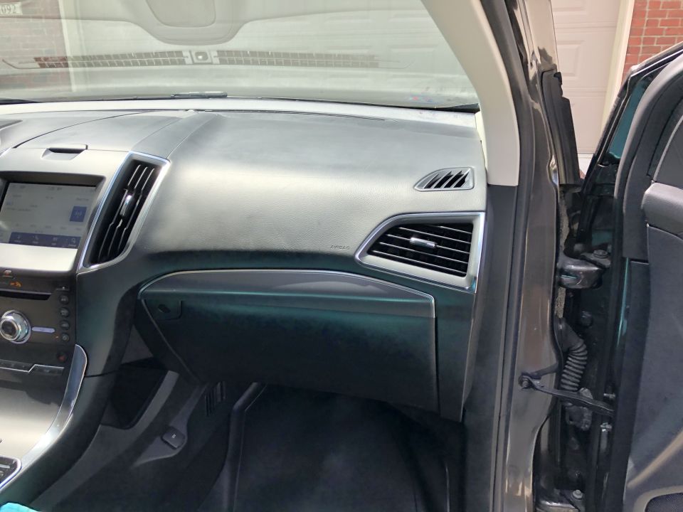 Interior dashboard and open driver's door of a modern SUV.