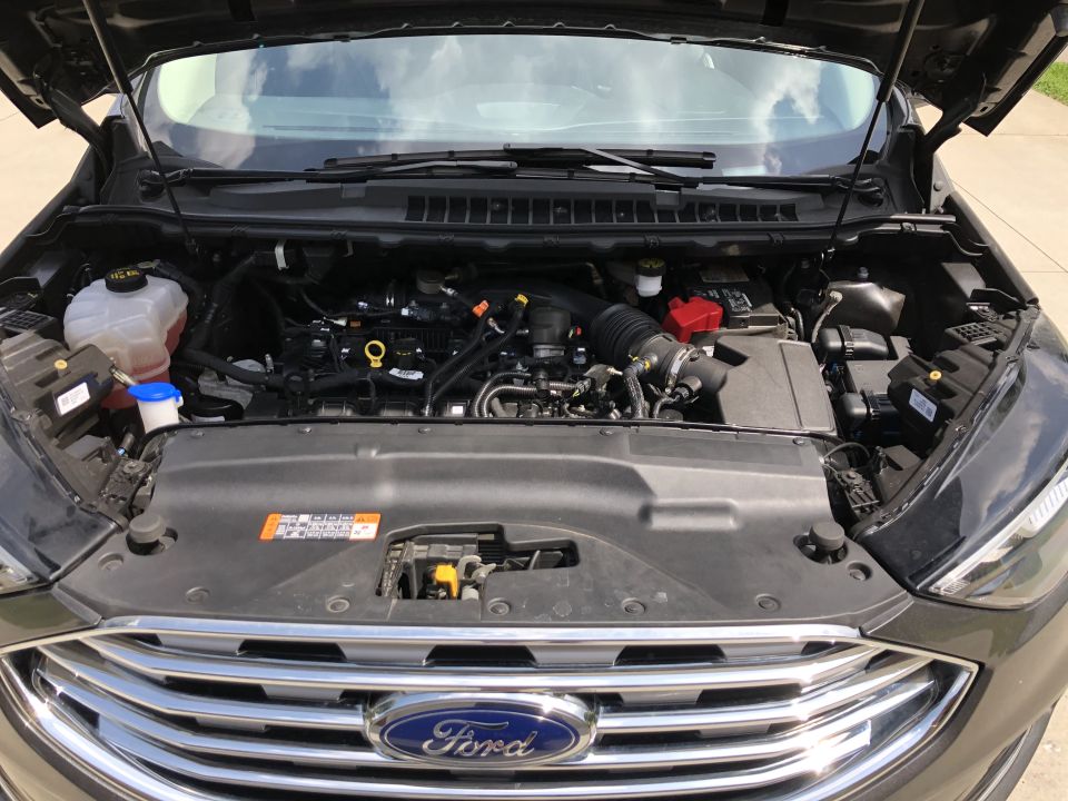 Dark gray Ford SUV engine bay with hood open, showing engine components and Ford logo on grille.
