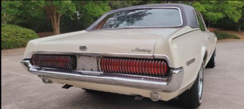 2008 Ford Focus - Rear 3/4 view of a cream-colored classic Mercury Cougar coupe with a black vinyl roof. The car features a full-width ribbed taillight assem…