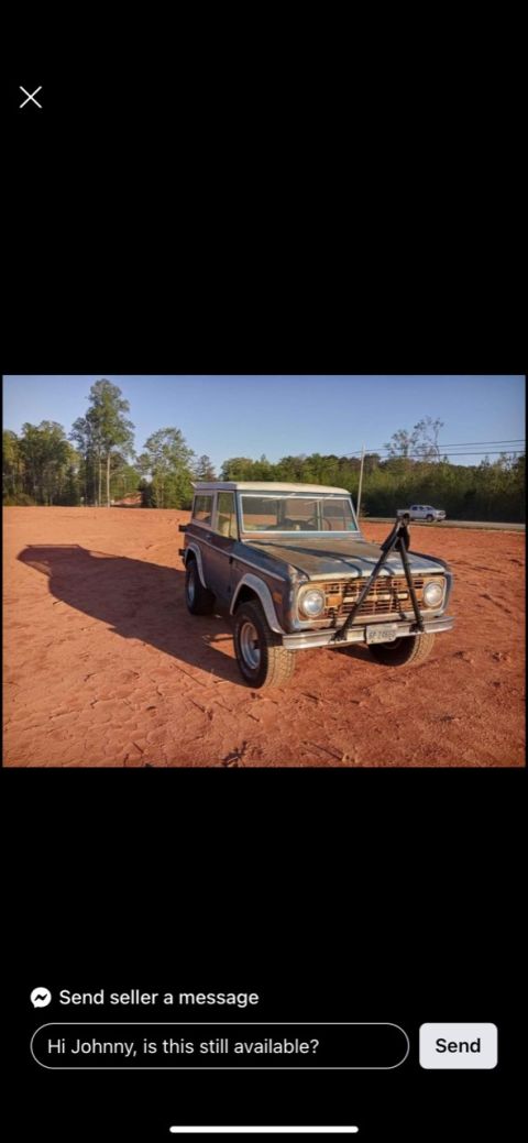 2008 Ford Focus - A vintage blue Ford Bronco is parked on a dirt lot with trees and a road in the background. A metal frame is attached to the front bumper.