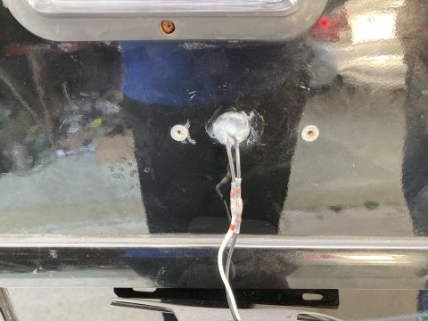 2015 Ford F-550 - A close-up view shows wires and a clear sealant applied around a hole in the black painted surface of a vehicle, likely for an aftermarket…