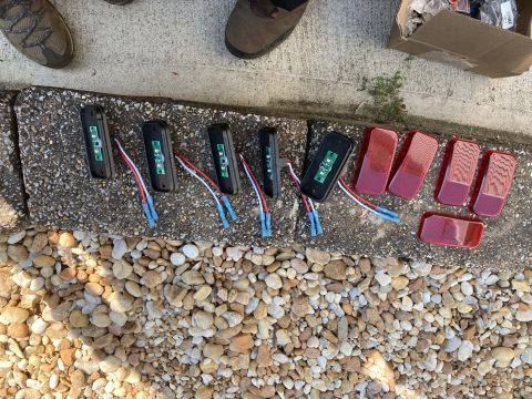 2015 Ford F-550 - Several black rectangular LED trailer lights with red lenses are laid out on a concrete curb next to a pile of small rocks. Some of the lig…