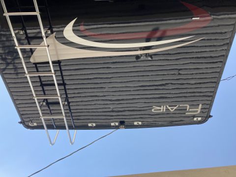 2015 Ford F-550 - The underside of a black RV with a silver ladder attached and the word "FLAIR" printed in white text. The RV has a graphic design with red…