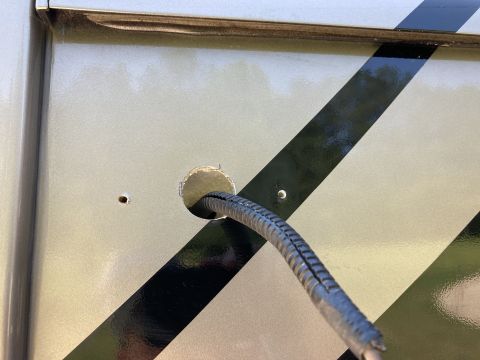 2015 Ford F-550 - A close-up view shows a black corrugated cable passing through a circular hole drilled into the side of a light-colored vehicle. The vehicl…