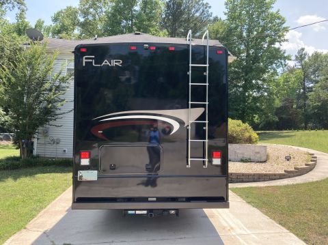 2015 Ford F-550 - Rear view of a black Fleetwood Flair RV parked on a concrete driveway. The RV has a silver ladder attached to the back and a Georgia licens…