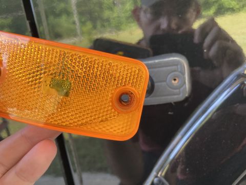 2015 Ford F-550 - A hand holds an orange aftermarket side marker light with a textured lens over a dark vehicle's fender. A gray mounting bracket is visible…