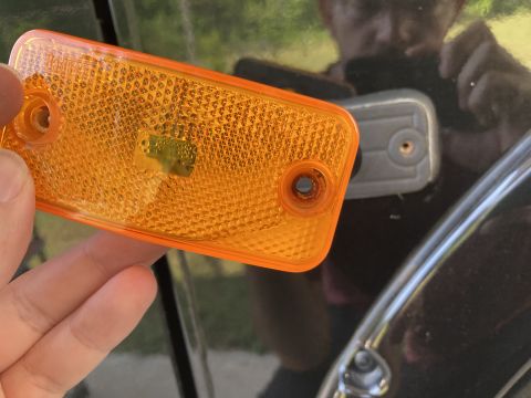 2015 Ford F-550 - A person is holding an orange rectangular reflector with two mounting holes. The reflector is positioned in front of a dark-colored vehicle…