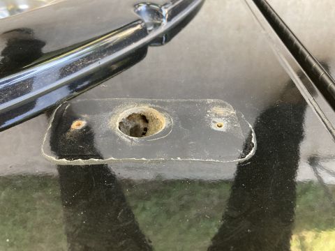 2015 Ford F-550 - A close-up view shows a black metal plate with a large, damaged central hole and two smaller screw holes on a black vehicle surface. The pl…