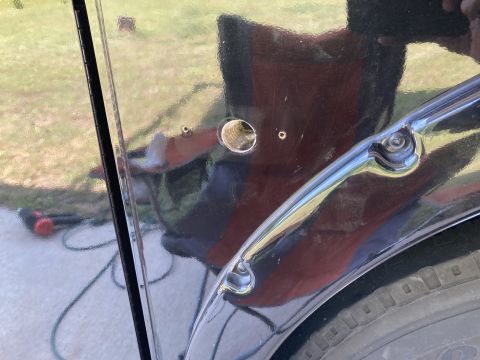 2015 Ford F-550 - A close-up view shows a hole drilled into the black painted body of a vehicle, with a chrome trim piece visible below it. A tire and part o…