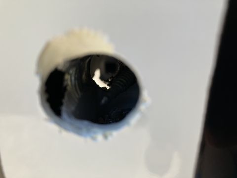 2015 Ford F-550 - A close-up view looking into a dark, corrugated pipe protruding from a white surface. The pipe appears to be insulated with a textured, off…