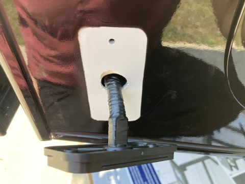 2015 Ford F-550 - A black, glossy surface with a white rectangular plate is visible. A black cable is fed through a hole in the plate and the surface, with a…