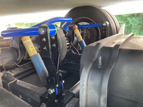 2015 Ford F-550 - The underside of a vehicle shows a modified suspension system with blue sway bars and yellow Bilstein shock absorbers. A large black fuel t…