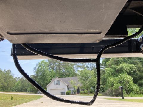 2015 Ford F-550 - A view of the underbody wiring harness of a vehicle, with a house and trees in the background.