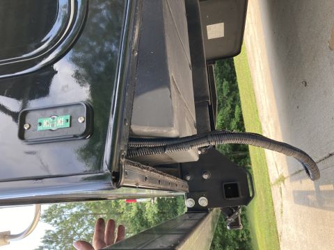 2015 Ford F-550 - Close-up view of the underbody of a black truck, showing a license plate light and a protective wiring conduit.