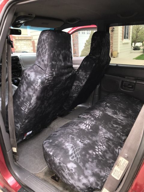 2000 Ford Explorer - The interior of a red Ford Explorer shows custom seat covers with a black and gray camouflage pattern on the front bucket seats and the rea…