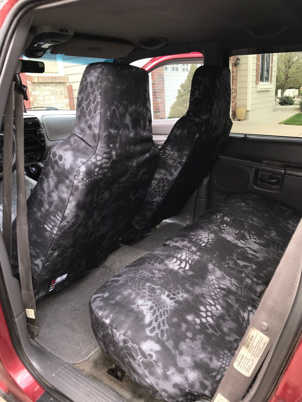 Interior of a red Ford Explorer with black and gray camouflage seat covers.