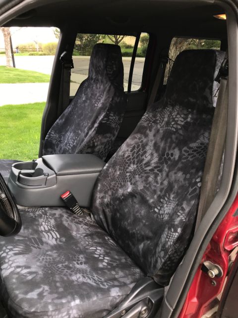 2000 Ford Explorer - The interior of a red SUV shows custom seat covers with a black and gray camouflage pattern on the front seats. The vehicle is parked outdo…