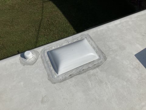 2015 Ford F-550 - A close-up view of a white RV roof shows a white vent and a white antenna with sealant around their bases. The RV roof is a light gray colo…