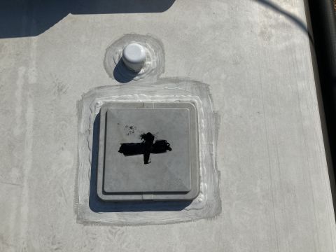 2015 Ford F-550 - A close-up view of a gray, square access panel on a light-colored surface, possibly a vehicle roof or RV exterior. The panel has a black cr…