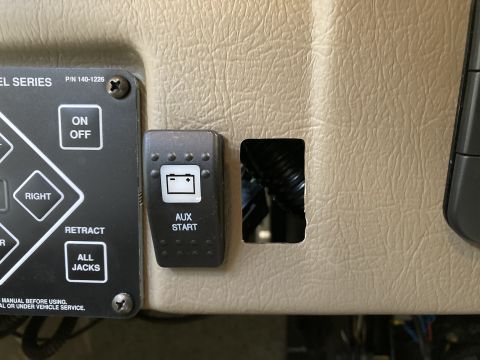 2015 Ford F-550 - A close-up view shows an auxiliary start switch with a battery icon and text that reads "AUX START" mounted to a tan dashboard panel. To th…