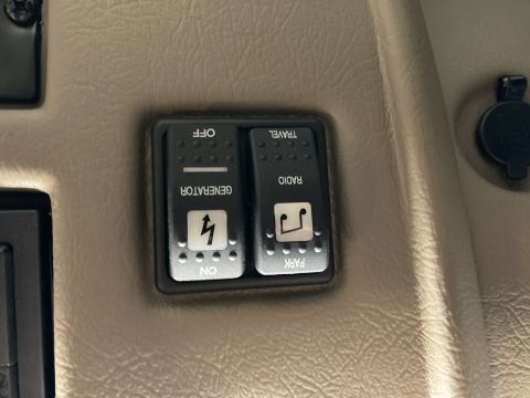 2015 Ford F-550 - Two toggle switches are mounted on a tan, textured surface. The left switch is labeled "GENERATOR" with an "ON" position indicated by a lig…