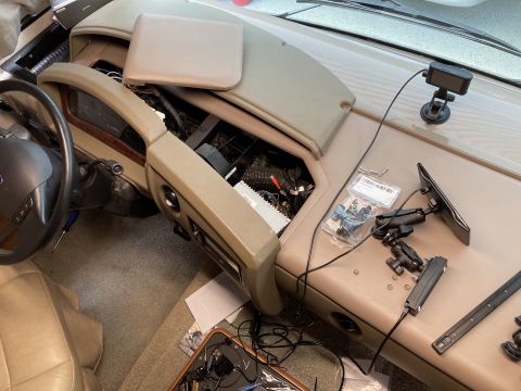 2015 Ford F-550 - Interior of a Ford pickup with the tan dash partially removed, exposing wiring, plus phone mounts and a Ford steering wheel.