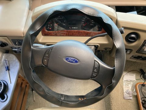 2015 Ford F-550 - Interior view of a Ford steering wheel with a cover, dashboard gauges, and wood trim details.