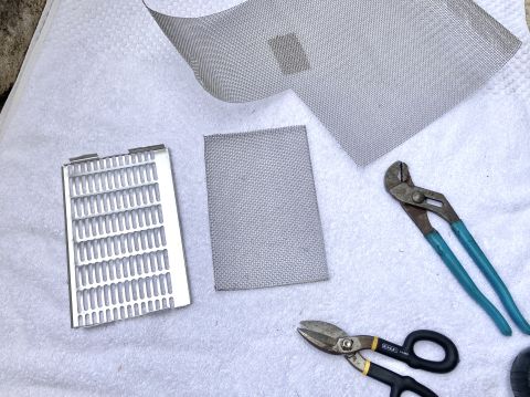 2015 Ford F-550 - Bug screen material and a metal grille are laid out with tools, suggesting preparation for installation or repair.