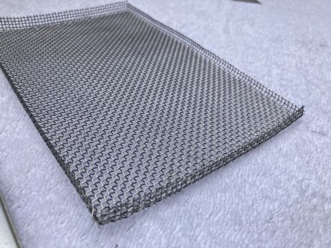 2015 Ford F-550 - A close-up view of a metal mesh screen, likely a bug screen, on a white textured background.