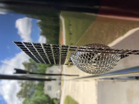 2015 Ford F-550 - Close-up of a chrome grille emblem and mesh screen, reflecting the sky and trees.